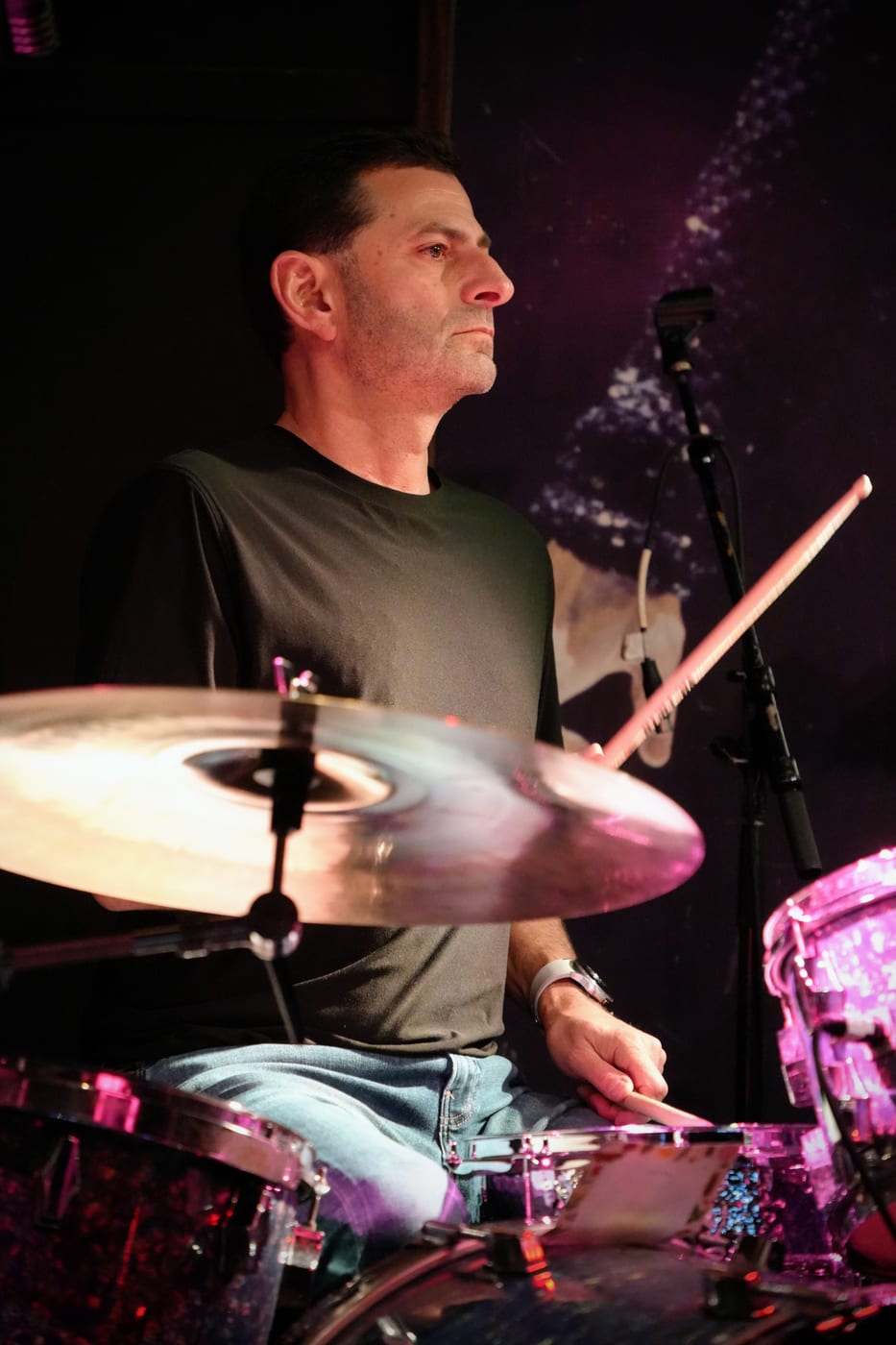 Drummer locked in, pink stage lighting